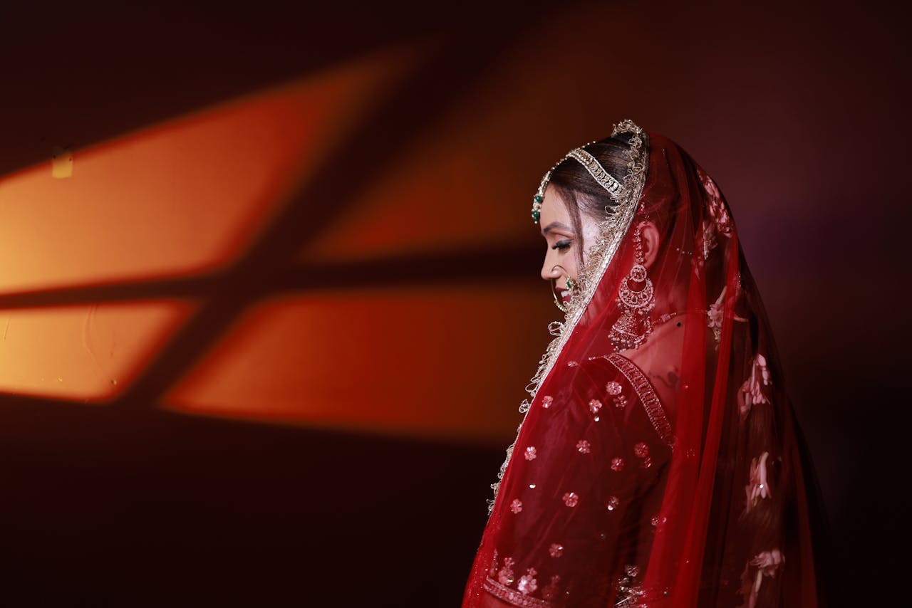 Stunning image of a bride in red traditional wear, artistically lit with warm colors.