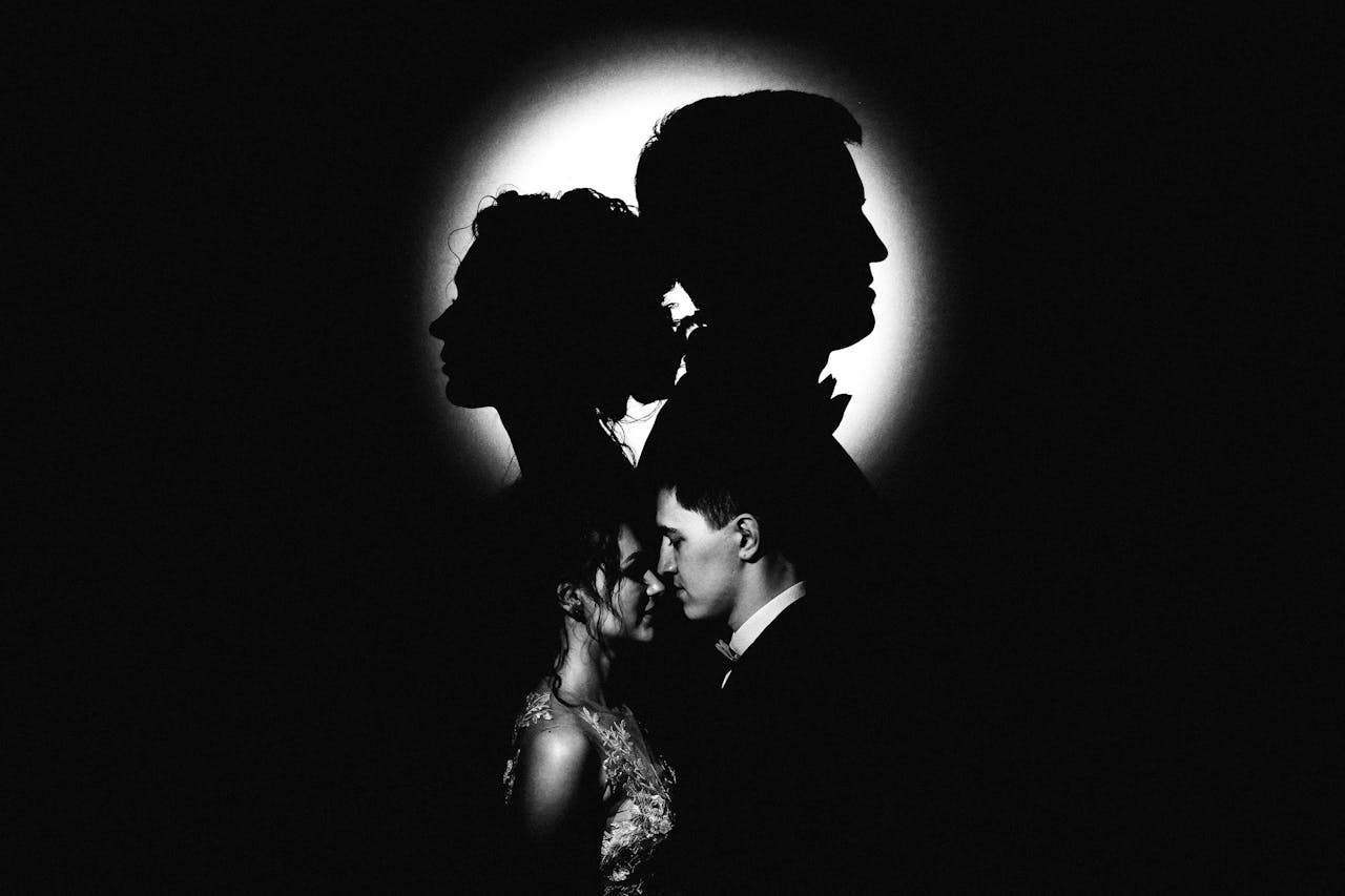 Artistic portrait of a couple in silhouette with contrasting light and shadow.